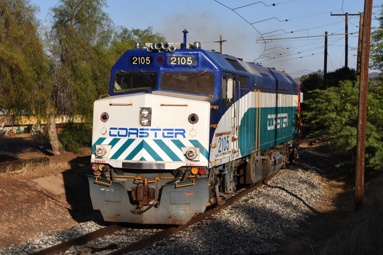 Front view of blue, white, and turquoise COASTER locomotive 2105 on the tracks.